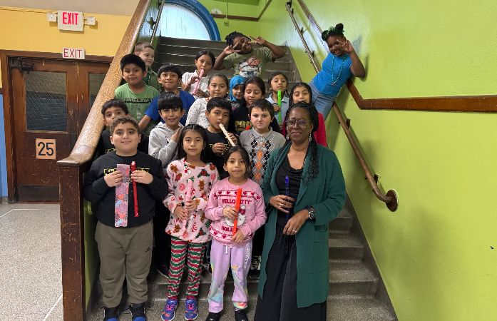  Ms. Thompson standing on the stairway with her students who are holding recorders